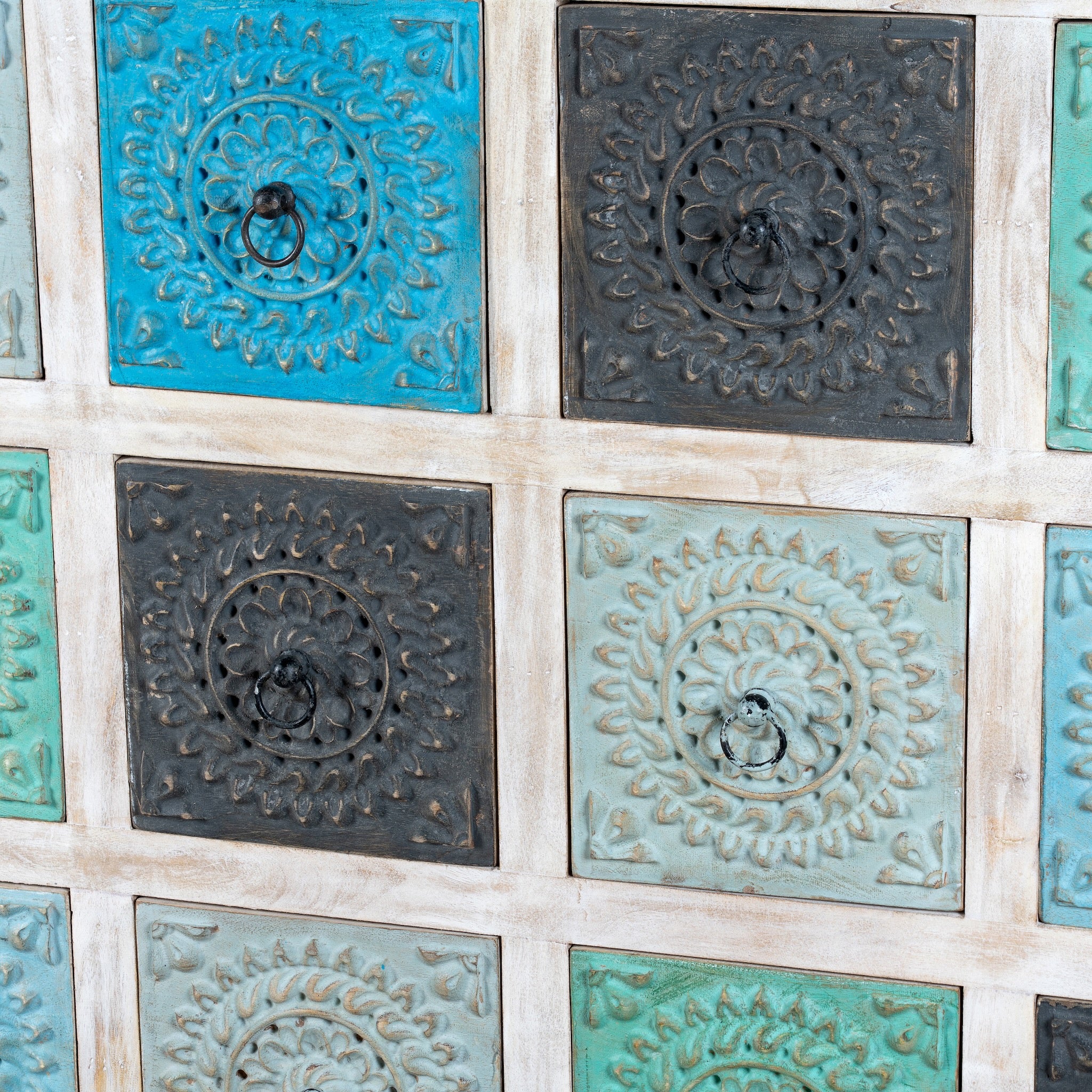 Close up image of a carved mango wood chest of drawers with twelve multicolour floral drawer fronts, 124 × 40 × 102 cm.