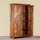 Side angle image of a Tash hand carved mango wood wardrobe with mandala carved doors, hanging rail and four storage compartments, 108x55x190cm