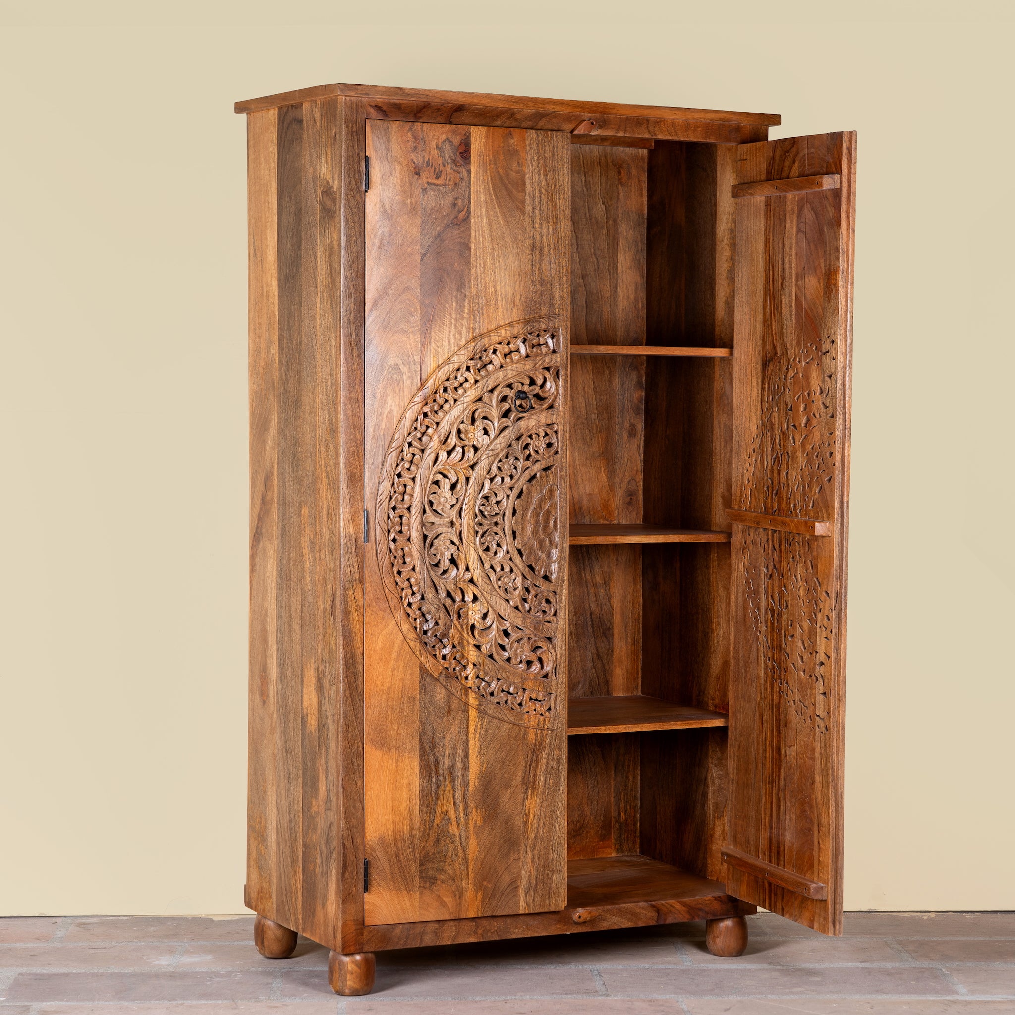 Side angle image of a Tash hand carved mango wood wardrobe with mandala carved doors, hanging rail and four storage compartments, 108x55x190cm