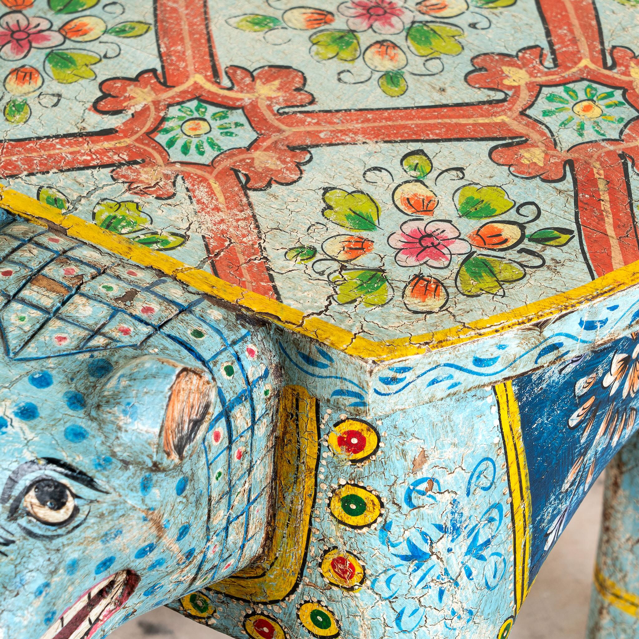 Close up image of a hand-painted wooden tiger side table featuring Indian folk art and floral details, shaped like a tiger with deity painting on top, perfect for vintage and India-inspired home accessories.