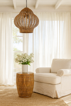 Life style imagination of a hand-carved mango wood coffee table with barrel shape and warm rustic finish; vintage style coffee table, 45 cm diameter, 55 cm height.