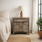 Lifestyle image of a hand painted bedside cabinet made of reclaimed wood with one drawer and two doors in sanskrit style.