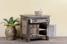 Side angle image with open door of a hand painted bedside cabinet made of reclaimed wood with one drawer and two doors in Sanskrit style.