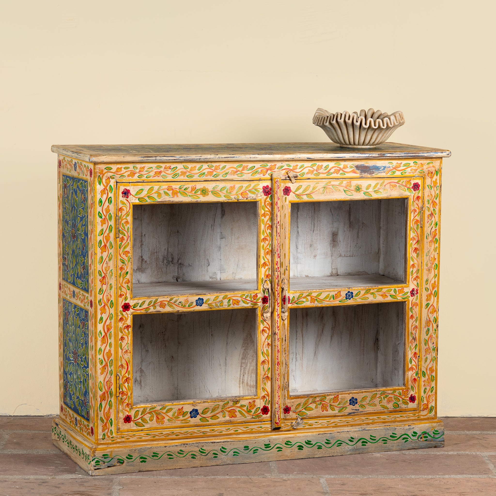 Side angle image of a Tushar hand-painted reclaimed wood display cabinet with colourful floral design and two doors 122cm