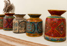Side angle image of a hand-painted papier-mâché vase Udanth in mixed colours with floral and folk motifs. A vintage home accessory and unique Indian decoration ideal for vintage home decor or use as a decorative statement vase.