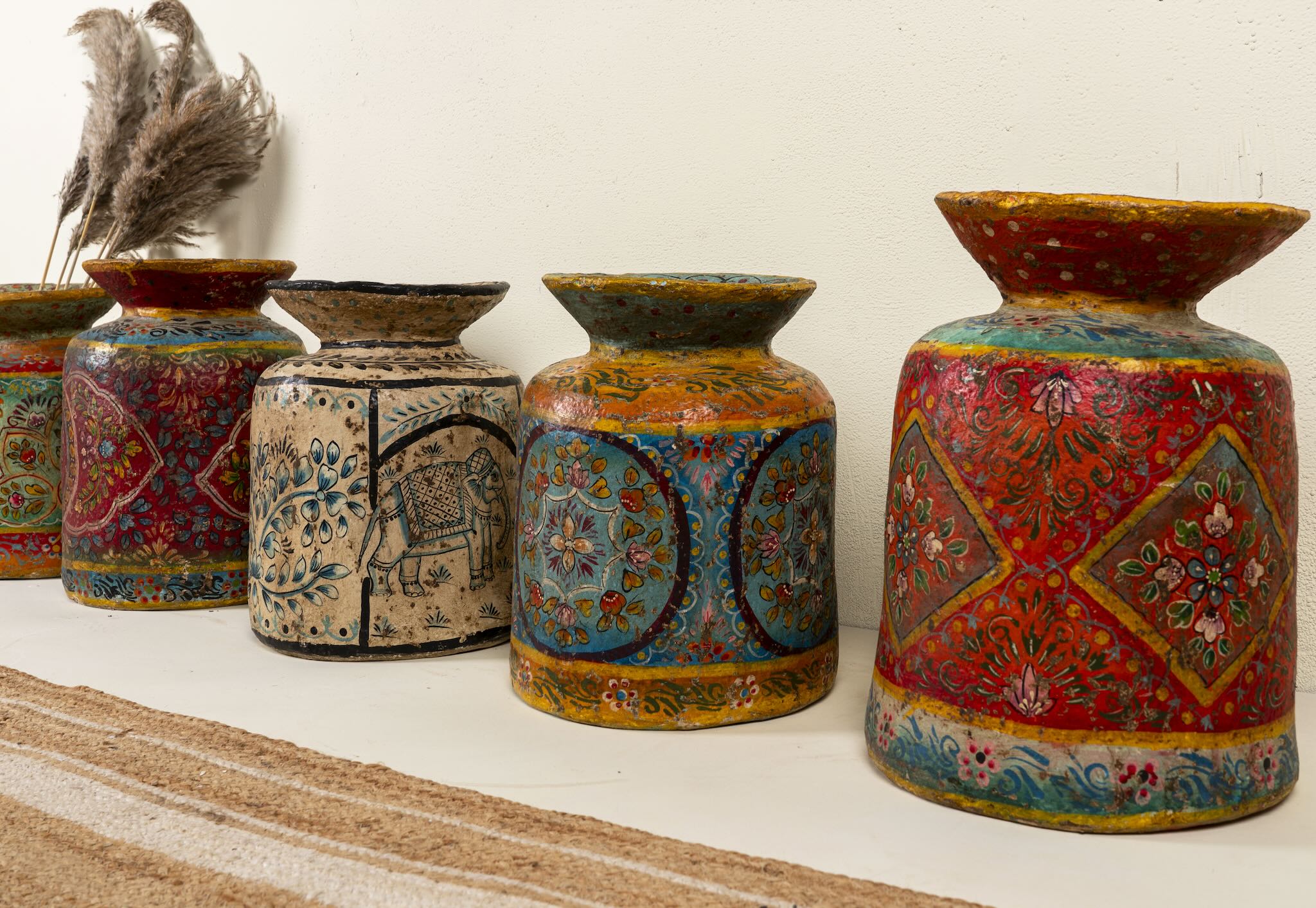 Side angle image of a hand-painted papier-mâché vase Udanth in mixed colours with floral and folk motifs. A vintage home accessory and unique Indian decoration ideal for vintage home decor or use as a decorative statement vase.