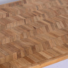 Close up image of a Uddanda mango wood dining table featuring an intricately patterned natural wood tabletop with a brass-plated iron base and contemporary industrial design, 181cm.