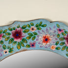 Close up image of a Ujjwal hand-painted round reclaimed wood mirror with colourful floral artwork, turquoise vintage frame, and artisan detailing, 90cm diameter.