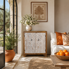 Lifestyle imagination of a hand-carved mango wood cupboard Utkarsh with whitewashed doors featuring palm tree and botanical motifs. A Mediterranean-inspired piece of Indian furniture combining artisan detail with practical storage.