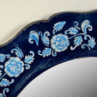 Close up image of a Uttam hand-painted round reclaimed wood mirror with deep blue floral frame, vintage artisan detailing, 90cm diameter.