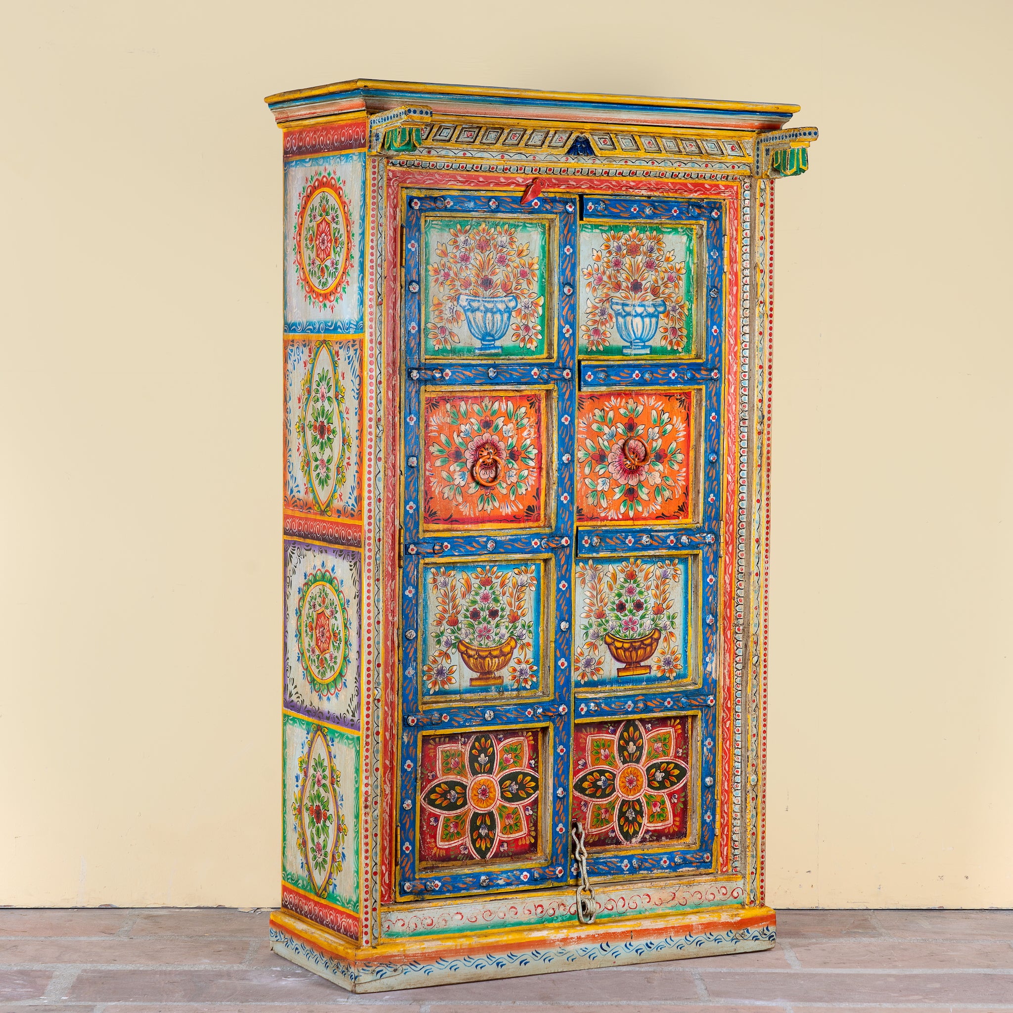 Side angle image of a hand-painted teak wood cabinet with floral motifs; teak wood furniture for bohemian interiors, 105 × 55 × 177 cm.