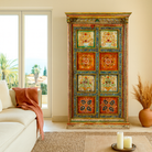 Lifestyle image of a hand-painted teak wood cabinet with floral motifs; teak wood furniture for bohemian interiors, 105 × 55 × 177 cm.