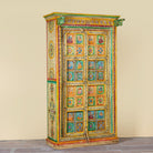 Side angle image of a hand painted wardrobe made of teak wood with floral motifs; unique furniture inspired by Indian artistry, 104 × 50 × 186 cm.