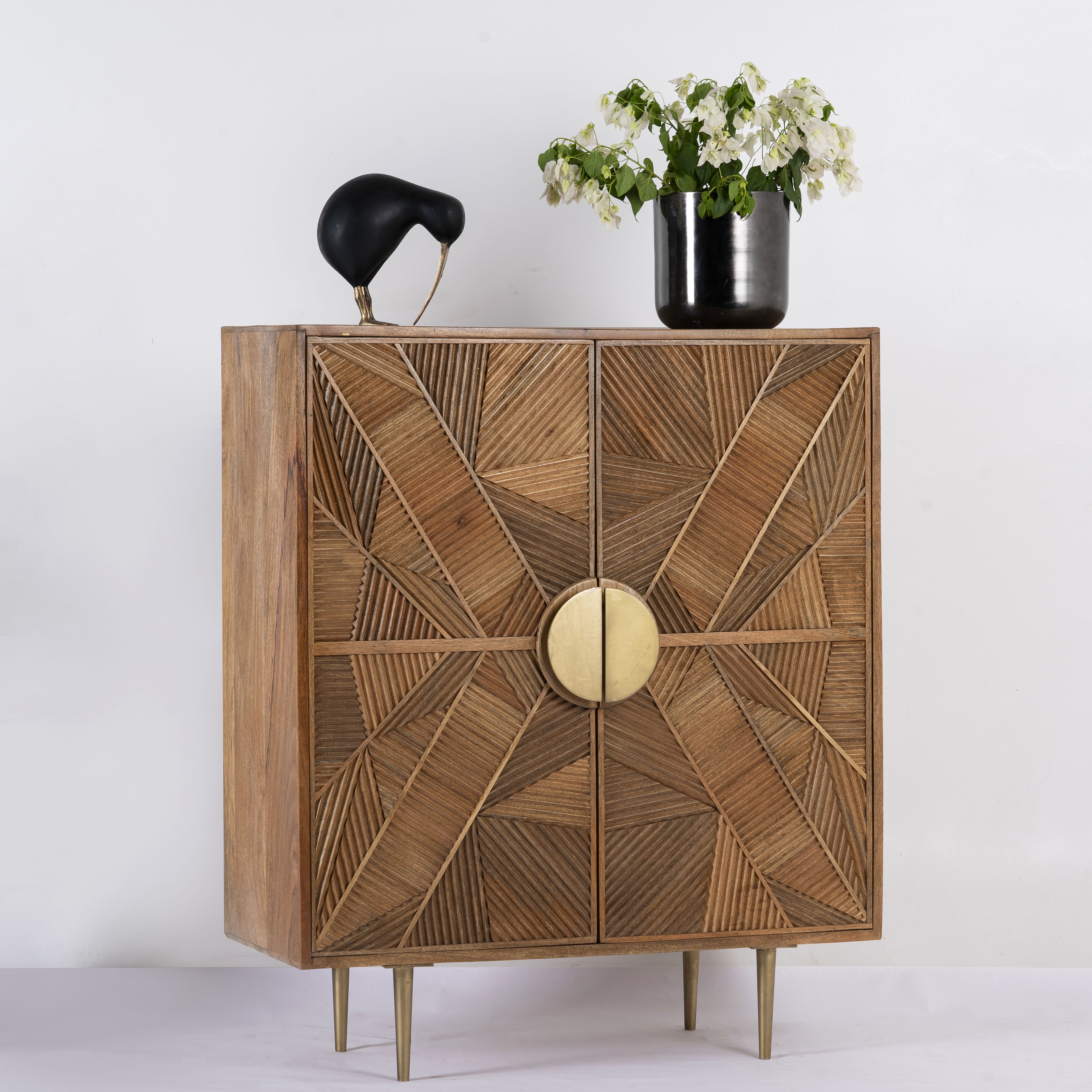 Side angle image of a natural mango wood cupboard with carved linear design and antique brass legs, 91 × 40 × 109 cm.