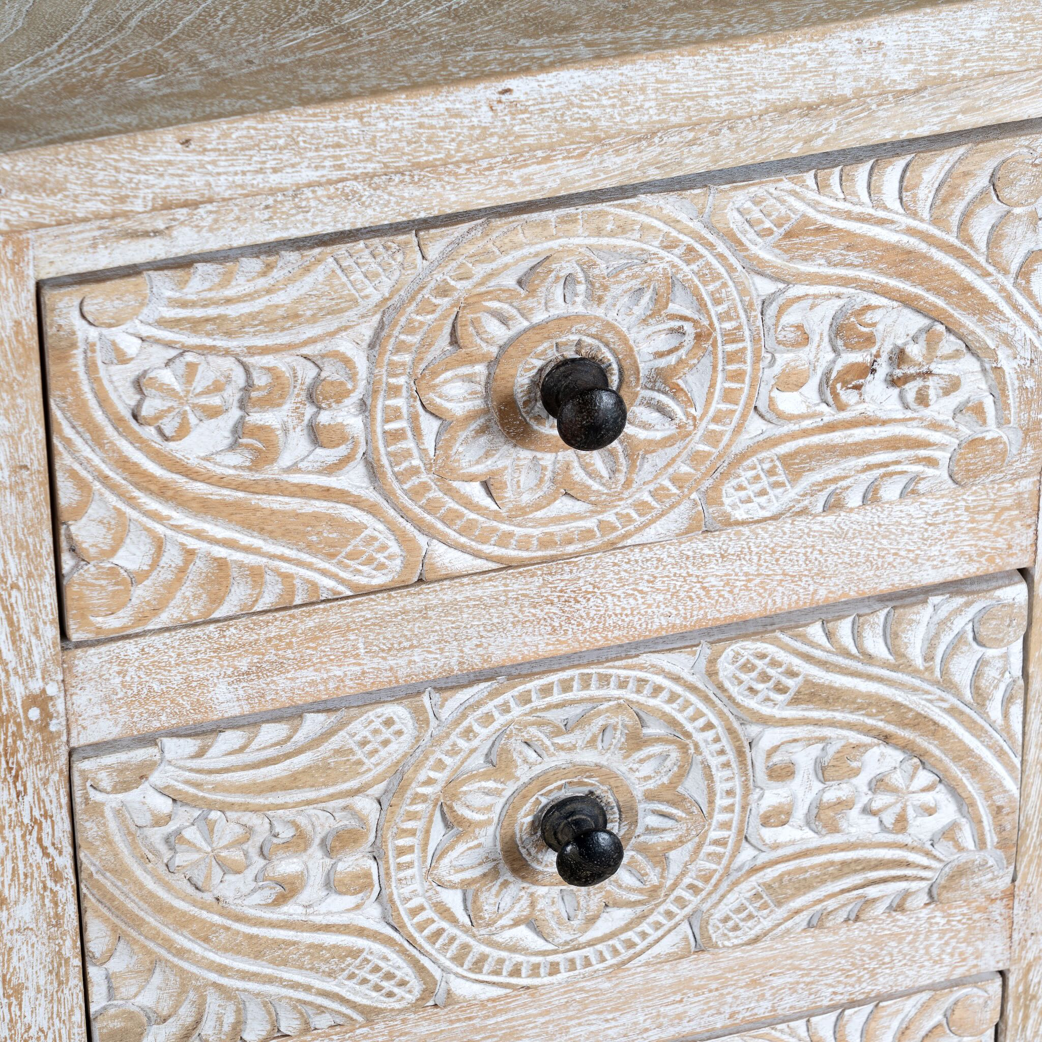 Close up image of a pair of mango wood nightstands Ved in a whitewashed vintage finish, featuring hand-carved drawer fronts with ornate circular and leafy motifs. Stylish and compact vintage-style bedside tables with three drawers for elegant storage.
