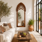 Lifestyle image of a Veeksha hand carved mango wood arch mirror with decorative openwork frame in teak wood finish, 85x15x197cm