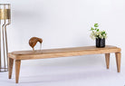 Side angle image of a minimalistic mango wood bench with natural finish and clean design; versatile wooden seating, 180 × 41 × 44 cm.