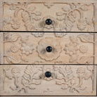 Close up image of a pair of mango wood nightstands Vihaan with hand-carved floral drawer fronts and a natural distressed finish. Elegant vintage-style bedside tables offering both storage and artisan-crafted detail.