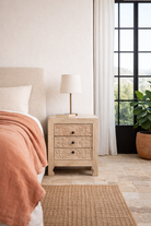 Lifestyle imagination of a pair of mango wood nightstands Vihaan with hand-carved floral drawer fronts and a natural distressed finish. Elegant vintage-style bedside tables offering both storage and artisan-crafted detail.