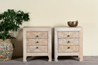 Lifestyle image of a pair of mango wood nightstands Vihaan with hand-carved floral drawer fronts and a natural distressed finish. Elegant vintage-style bedside tables offering both storage and artisan-crafted detail.