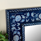 Close up image of a Vihana hand-painted reclaimed wood wall mirror with deep blue floral frame, artisan detailing, and vintage Indian character, 90x90cm.