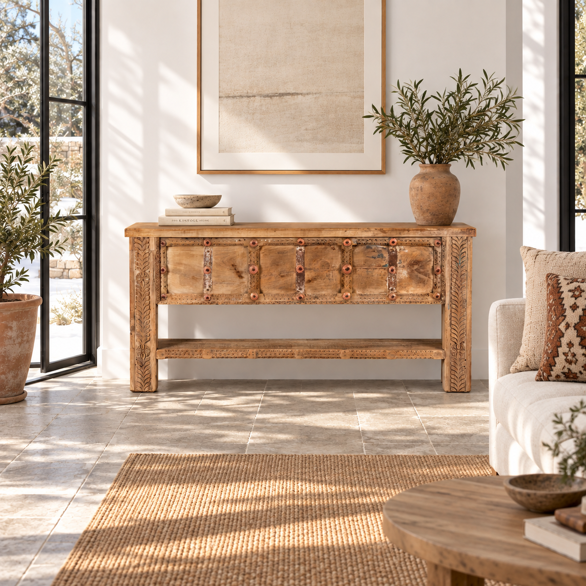 Lifestyle image of a Vihanraj reclaimed teak wood console table with original Indian door front, iron fittings and lower storage shelf 178cm