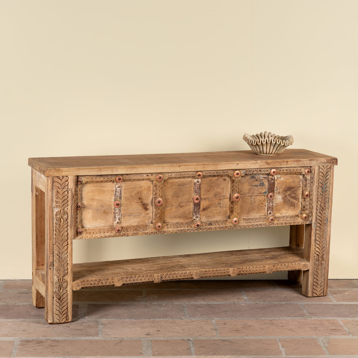 Side angle image of a Vihanraj reclaimed teak wood console table with original Indian door front, iron fittings and lower storage shelf 178cm