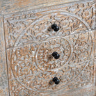 Close up image of a pair of hand-carved mango wood nightstands Vikram with three drawers each, showcasing intricate floral motifs in a distressed vintage-style finish. Elegant and functional bedside tables with timeless artisan appeal.