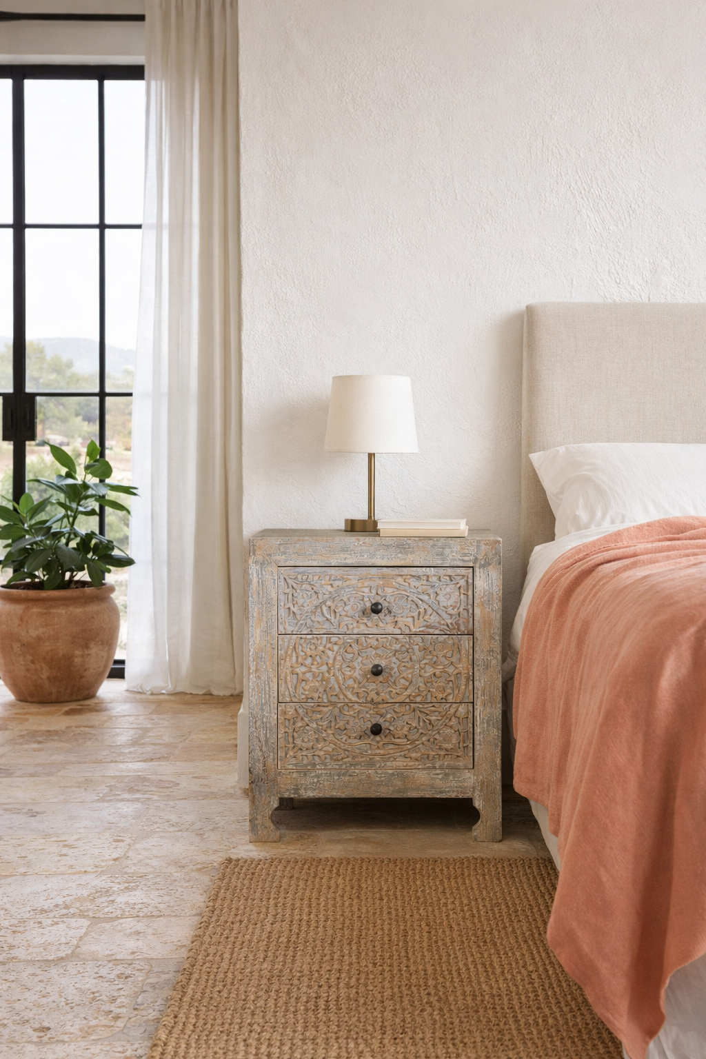Lifestyle imagination of a pair of hand-carved mango wood nightstands Vikram with three drawers each, showcasing intricate floral motifs in a distressed vintage-style finish. Elegant and functional bedside tables with timeless artisan appeal.
