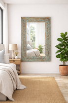 Lifestyle imagination of a carved mango wood mirror Anila with turquoise finish and hand-carved floral motifs. A bold and colorful addition to vintage home decor and Indian-inspired interiors.