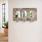 Lifestyle imagination of a triple arched hand-carved wooden mirror with distressed brown and white finish and three candle holders – ideal for Indian and vintage home accessories.