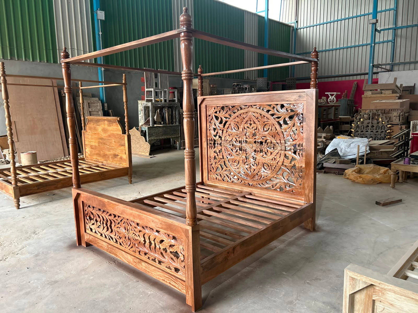 Factory image of a Vishika hand carved mango wood four poster bed with teak finish, ornate floral carved headboard and footboard, for 180x200cm mattress.