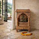 Lifestyle imagination of a handcrafted old teak wood home temple with carved details and drawer, ideal for religious items and Indian spiritual home accessories.