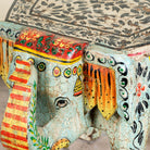 Close up image of a hand-painted wooden elephant-shaped side table with Indian folk art motifs and floral details, perfect for vintage or global home decor. 