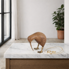 Lifestyle image of a handcrafted wooden kiwi bird sculpture Kiwi Petite with brass feet and beak. A vintage home accessory and unique Indian decoration ideal for shelves, desks, or vintage home decor styling.