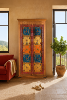 Lifestyle image of a hand-painted cabinet made from reclaimed teak wood with colourful Indian motifs – sustainable furniture and vintage teak wood craftsmanship for bold interiors.