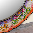 Close up image of a Yagna hand-painted round reclaimed wood mirror with colourful floral artwork, scalloped vintage frame, and artisan detailing, 90cm diameter.