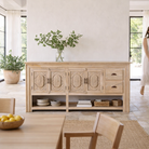 Lifestyle image of a of a hand-carved mango wood console table Zahira with 2 drawers and 4 doors in a natural finish. Elegant living room furniture piece with artistic detailing and practical storage.