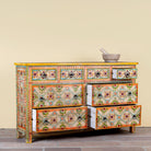 Side angle image with open drawers of a Ziya hand‑painted chest of 8 drawers made from reclaimed wood with floral motifs and iron handles—an artisan piece of painted wooden furniture.