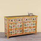 Side angle image of a Ziya hand‑painted chest of 8 drawers made from reclaimed wood with floral motifs and iron handles—an artisan piece of painted wooden furniture.