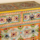 Close up image of a Ziya hand‑painted chest of 8 drawers made from reclaimed wood with floral motifs and iron handles—an artisan piece of painted wooden furniture.