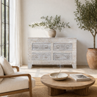Lifestyle imagination of a handcrafted chest of drawers Zuber made from reclaimed wood, featuring four carved drawers with circular motifs and a whitewashed finish. A rustic, sustainable furniture piece with soft texture and elegant detailing.