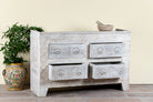 Side angle image with open drawers of a handcrafted chest of drawers Zuber made from reclaimed wood, featuring four carved drawers with circular motifs and a whitewashed finish. A rustic, sustainable furniture piece with soft texture and elegant detailing.