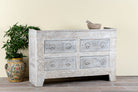Side angle image of a handcrafted chest of drawers Zuber made from reclaimed wood, featuring four carved drawers with circular motifs and a whitewashed finish. A rustic, sustainable furniture piece with soft texture and elegant detailing.