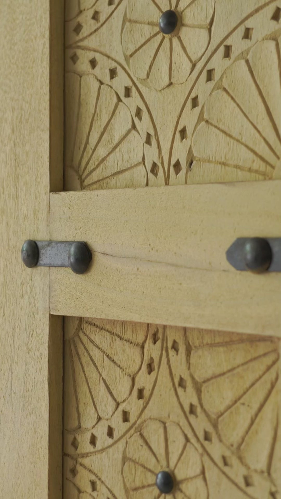 Sliding door panel made from reclaimed wood with detailed hand carvings and traditional iron fittings, combining rustic elegance with functional design.

