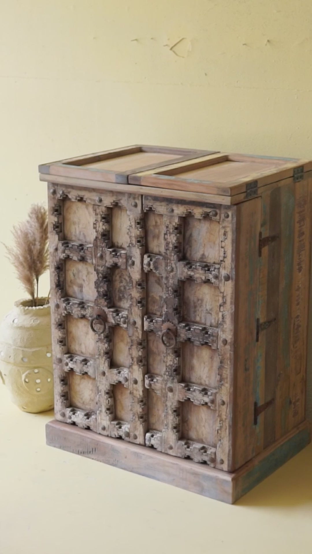 Foldable bar table made of reclaimed teak wood with inside storage and old door front.