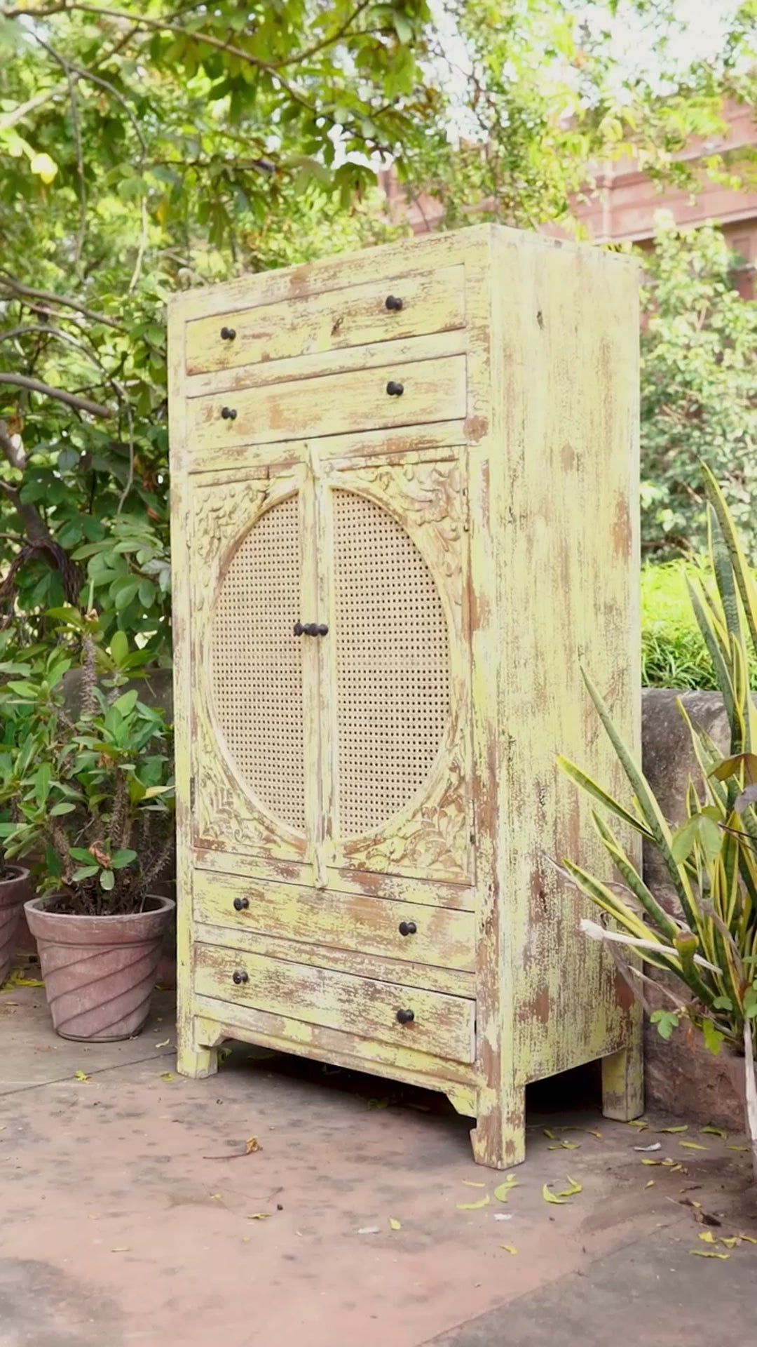 Reel showing a green-washed mango wood cabinet with floral carvings, rattan door inserts, versatile living room furniture, 80 × 148 × 40 cm.