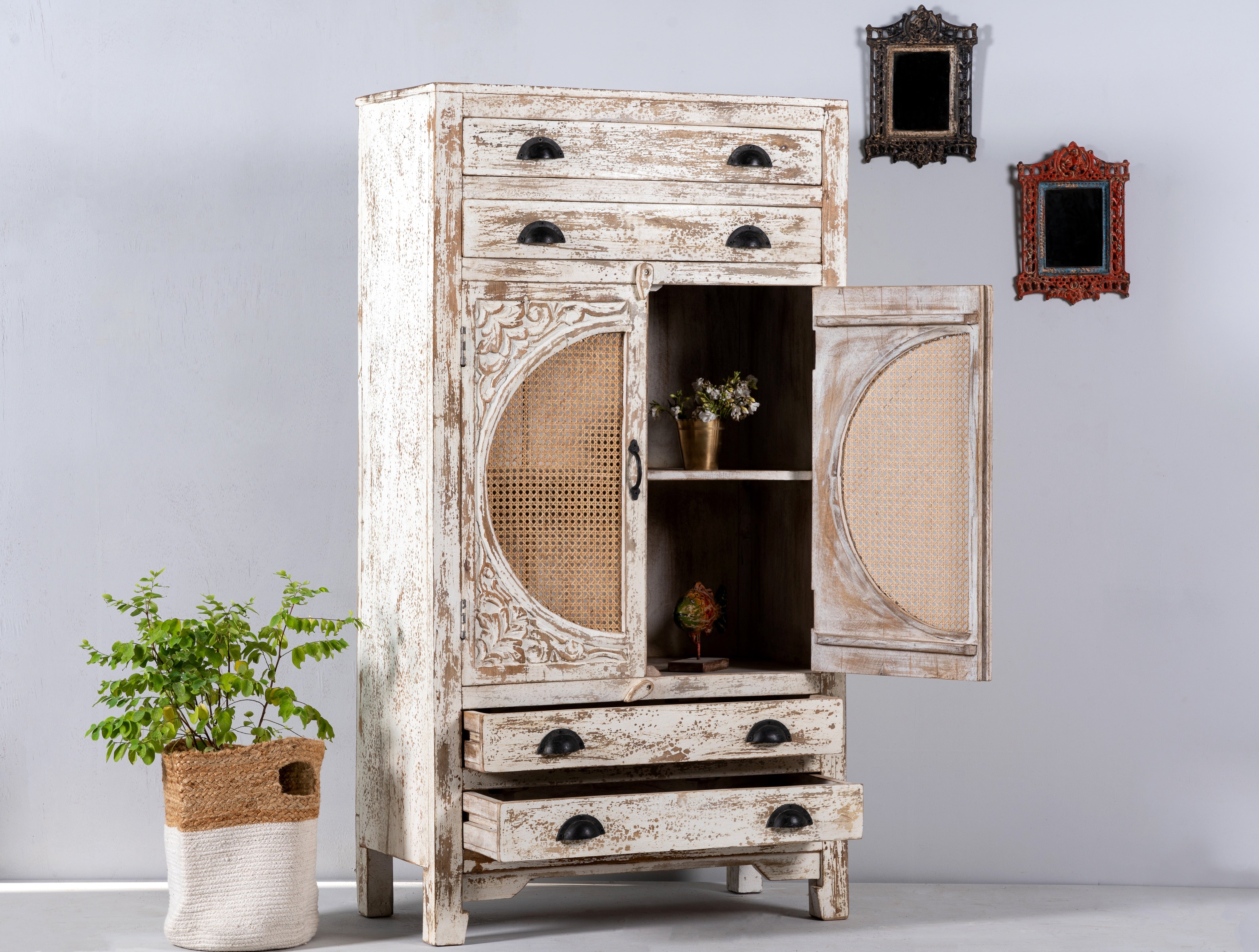 Side angle image of a Ahalya handcrafted solid mango wood cabinet with hand-carved floral doors, natural rattan inserts, four drawers, two storage compartments, and Mediterranean-inspired design, 148cm.
