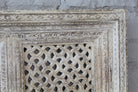 Close up image of a square mango wood wall panel Akupara with intricate hand-carved detailing in soft, natural tones. A piece of unique wooden wall art perfect for wood wall decoration and carved wood furniture collections.