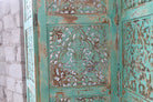 Close up image of a hand-carved green mango wood folding room divider with delicate carved patterns, natural variations, and warm boho style for unique interiors.